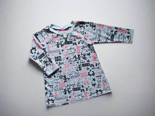 Long-sleeve shirt with text and graphic design on a wooden surface